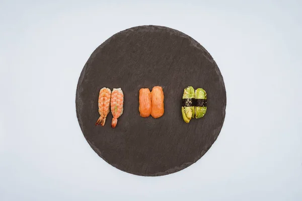 Vue de dessus de délicieux sushis sur panneau d'ardoise isolé sur blanc — Photo de stock