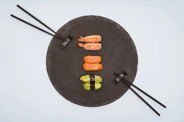 Вид на вкусные суши на доске и палочки для еды, изолированные на белом — стоковое фото