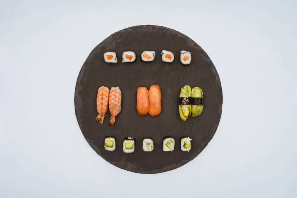 Top view of various delicious sushi on slate board isolated on white — Stock Photo