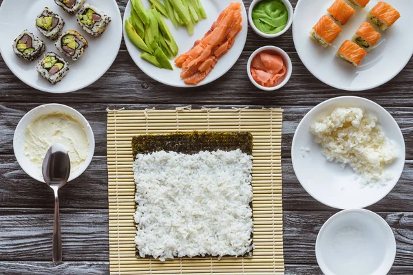 Вид зверху на рис, норі та інгредієнти для суші на дерев'яному столі — стокове фото