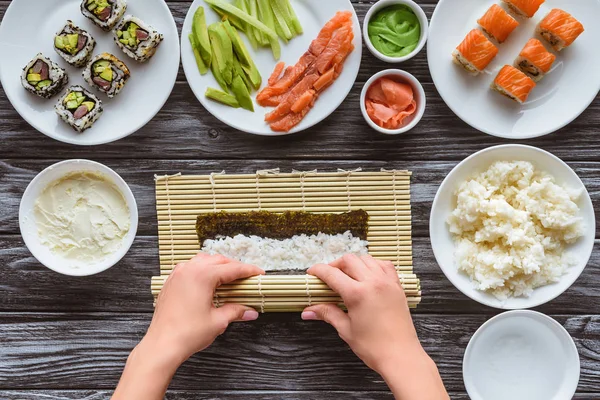 Vista superior parcial de la persona que cocina rollo de sushi gourmet - foto de stock