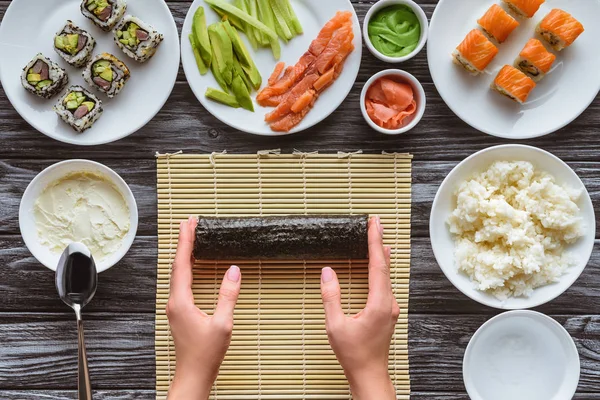 Colpo ritagliato di persona che prepara delizioso rotolo di sushi — Foto stock