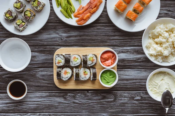 Top view of delicious sushi rolls with ingredients on wooden table — Stock Photo