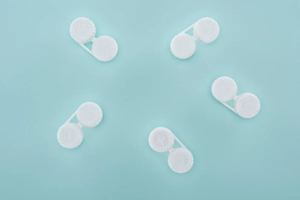 Flat lay with contact lenses in containers arranged on blue background — Stock Photo