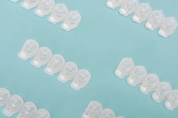 Top view of contact lenses in containers arranged on blue background — Stock Photo