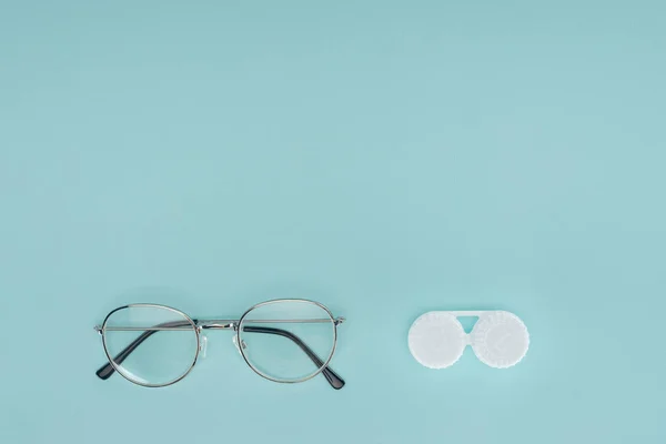 Vista superior de óculos e lentes de contato recipiente no fundo azul — Fotografia de Stock