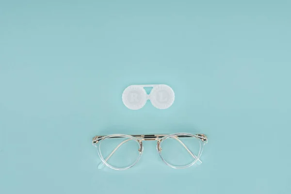 Vista superior del envase de anteojos y lentes de contacto sobre fondo azul - foto de stock
