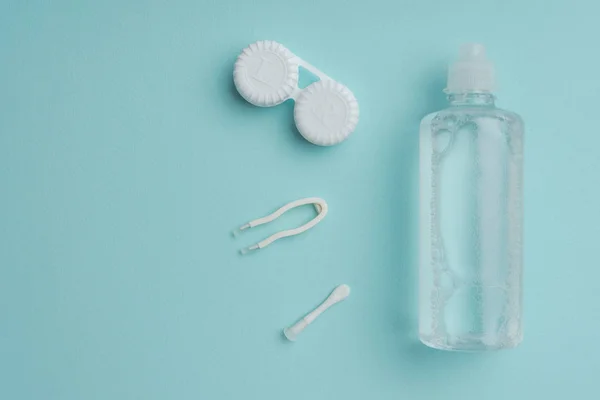 Ansicht steriler Flüssigkeit in Flasche, Pinzette und Behälter für Kontaktlinsen auf blauer Tischplatte — Stockfoto