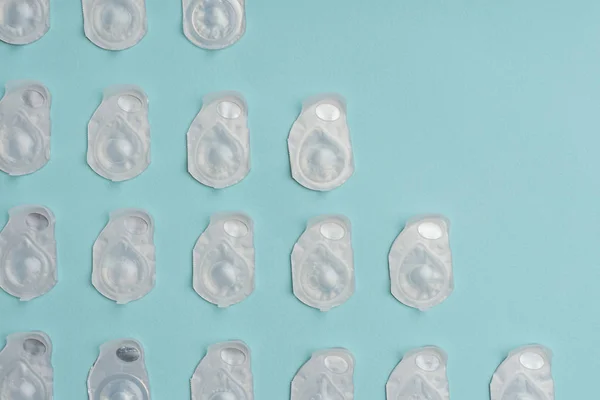 Cadre complet de lentilles de contact dans des récipients disposés sur fond bleu — Photo de stock