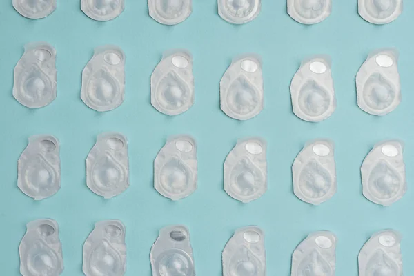 Flat lay with contact lenses in containers arranged on blue background — Stock Photo