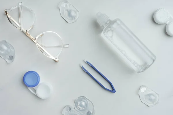 Top view of arrangement with eyeglasses and contact lenses storage supplies on white surface — Stock Photo