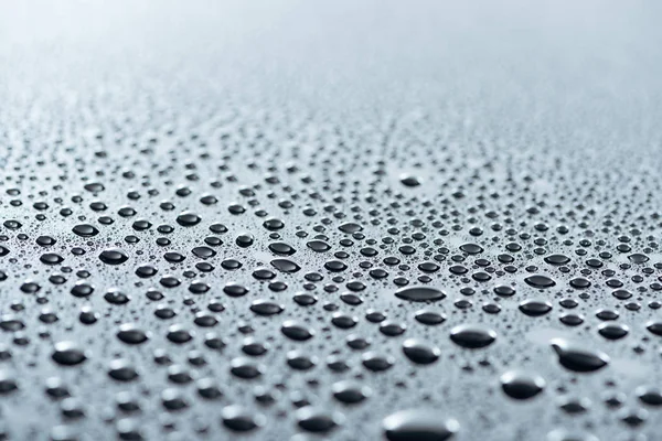 Nahaufnahme von Wassertropfen auf grauer Oberfläche als Hintergrund — Stockfoto