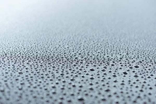 Vue rapprochée des gouttes d'eau sur la surface grise comme fond — Photo de stock