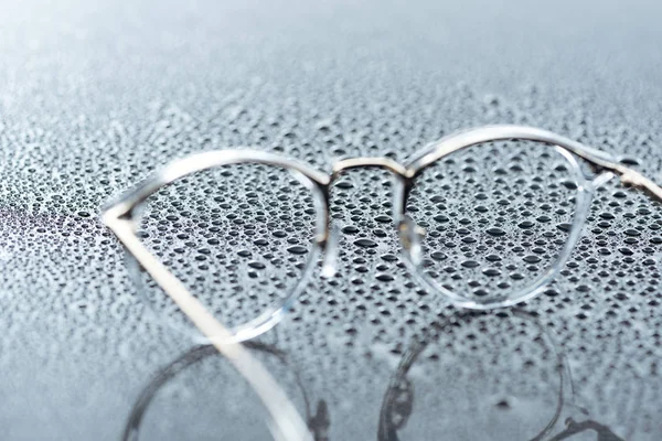 Vista de cerca de las gafas y gotas de agua sobre fondo gris - foto de stock