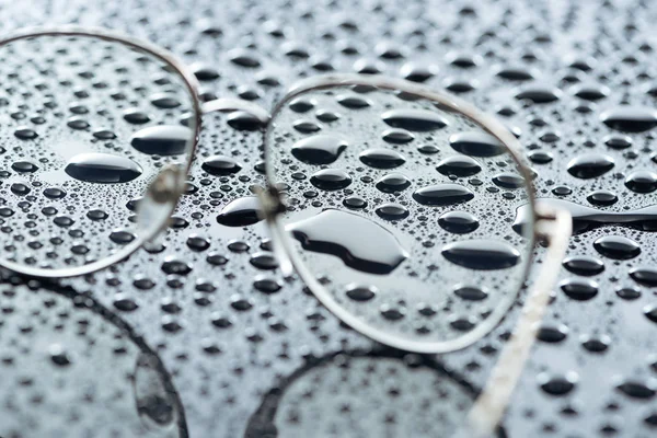 Close up view of eyeglasses and water drops on grey backdrop — Stock Photo