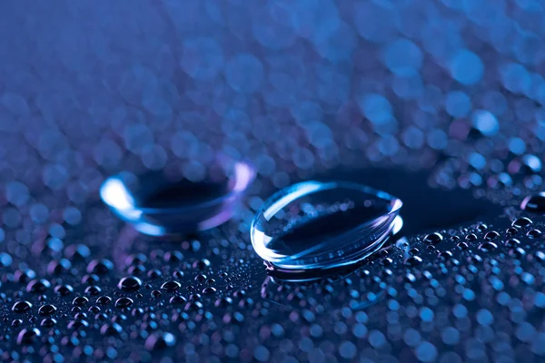 Foco seletivo de lentes de contato e gotas de água no fundo azul — Fotografia de Stock