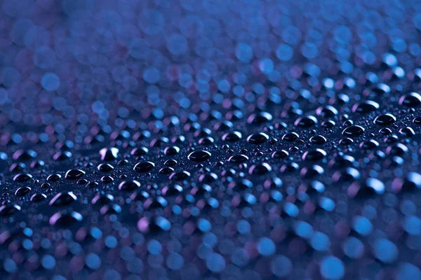 Vista de cerca de las gotas de agua en la superficie azul como fondo - foto de stock