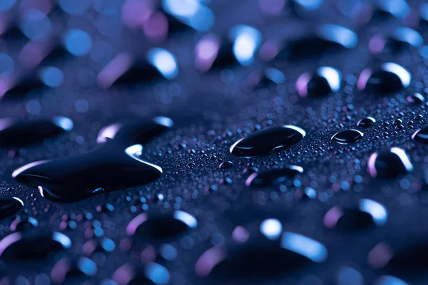 Vue rapprochée des gouttes d'eau sur la surface bleue comme fond — Photo de stock