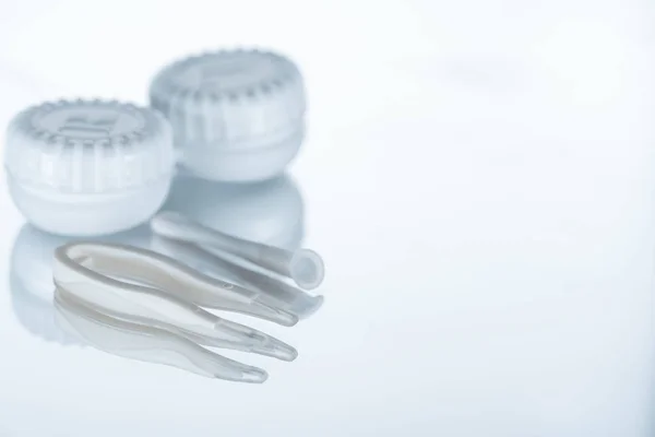 Close up view of container for contact lenses and tweezers on background with reflection — Stock Photo