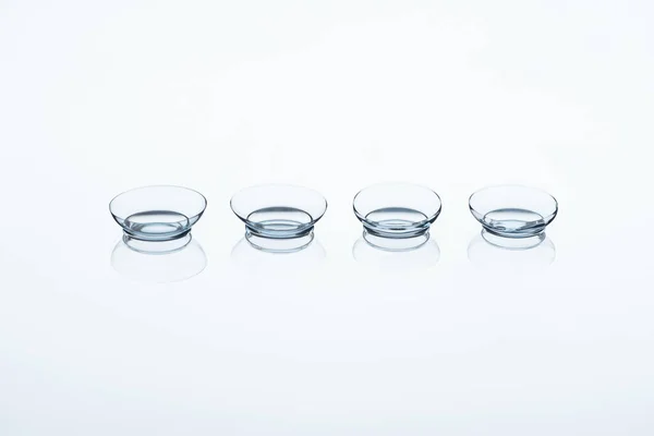 Vista de cerca de las lentes de contacto dispuestas sobre fondo blanco - foto de stock