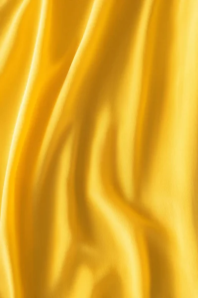 Полный кадр из волнистой желтой шелковой ткани в качестве фона — стоковое фото