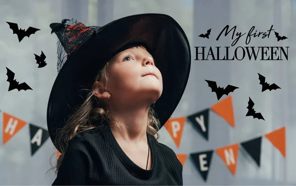 Ritratto di adorabile bambino in costume da strega di Halloween guardando lontano a casa con la scritta 