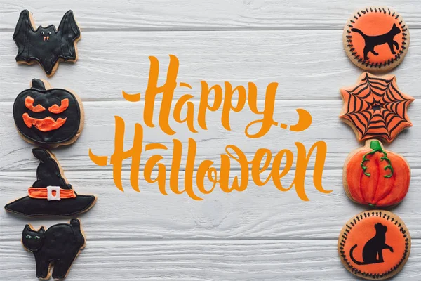 Vista elevada de galletas de halloween hechas en casa colocadas en filas sobre fondo de madera blanca con letras de 