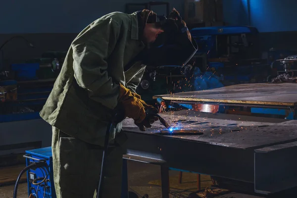 Fabricación concentrada trabajador soldadura de metal con chispas en la fábrica - foto de stock