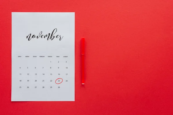 Vue du haut du calendrier de novembre et marqueur isolé sur rouge avec espace de copie, concept du vendredi noir — Photo de stock