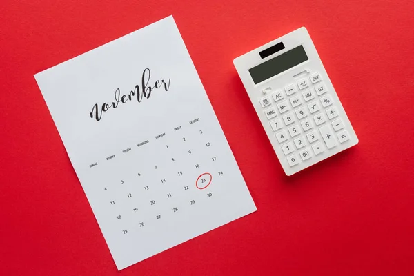 Top view of calendar for November and calculator isolated on red, black friday concept — Stock Photo