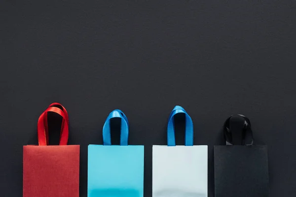 Top view of colorful shopping bags on black background with copy space for black friday — Stock Photo