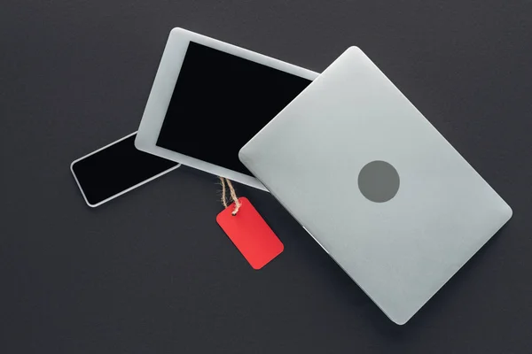 Top view of digital devices with red sale tag on black — Stock Photo