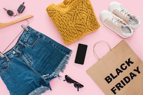 Ansicht von stylischer Kleidung, Smartphone, Autoschlüssel und Einkaufstasche mit schwarzem Freitag-Schild — Stockfoto