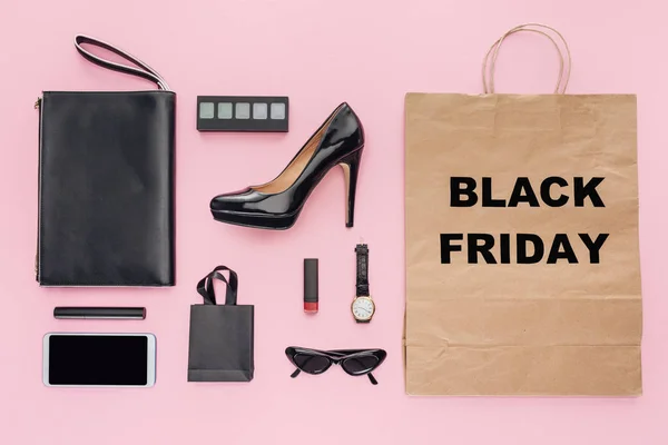 Flat lay with accessories and shopping bag with black friday sign isolated on pink — Stock Photo