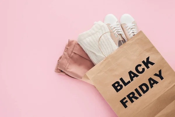 Top view of clothes in shopping bag with black friday symbol isolated on pink — Stock Photo