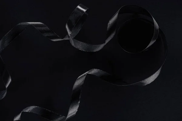 Верхний вид черной глянцевой ленты на черном фоне — стоковое фото