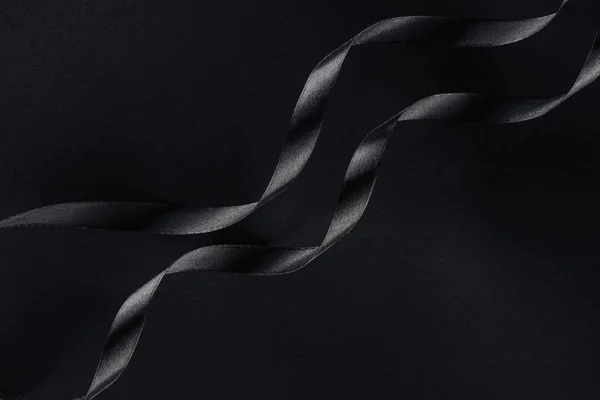 Top view of two glossy ribbons on black background — Stock Photo