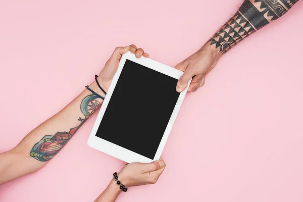 Vista recortada de los clientes tirando de la tableta digital con pantalla en blanco aislado en rosa - foto de stock