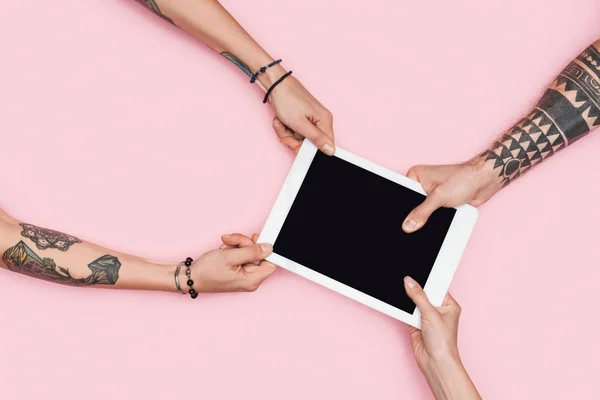 Partial view of shopaholics pulling digital tablet with blank screen isolated on pink — Stock Photo