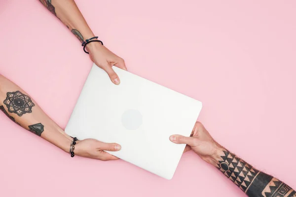 Cropped view of tattooed people pulling laptop during sale isolated on pink — Stock Photo
