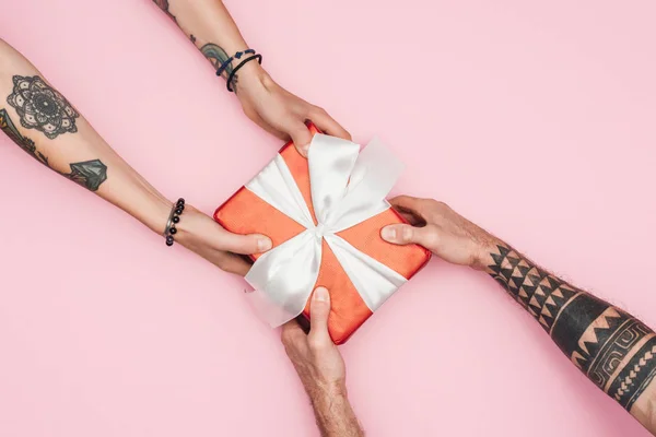 Cropped view of people holding gift box isolated on pink — Stock Photo