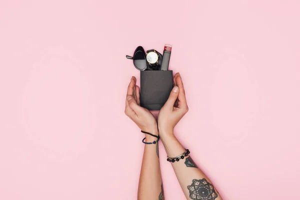 Abgeschnittene Ansicht tätowierter Frau mit kleiner Einkaufstasche mit Accessoires und Lippenstift isoliert auf rosa — Stockfoto