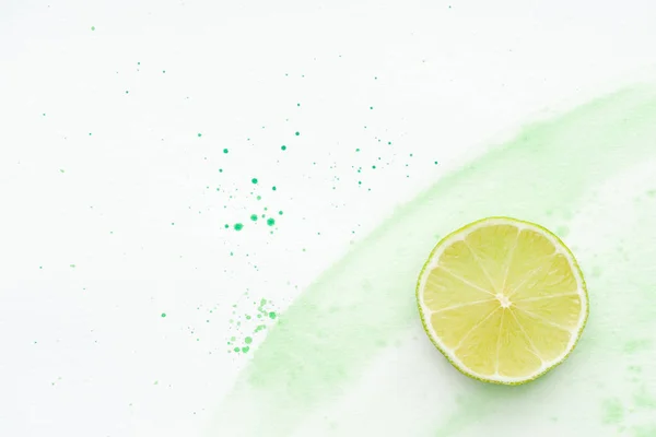 Vue de dessus du morceau de chaux mûre sur la surface blanche avec aquarelle verte — Photo de stock