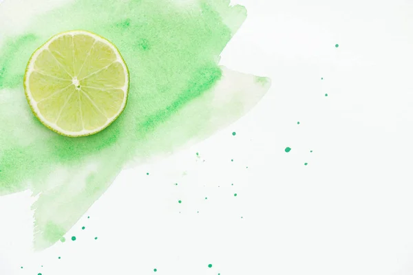 Top view of piece of tasty lime on white surface with green watercolor — Stock Photo