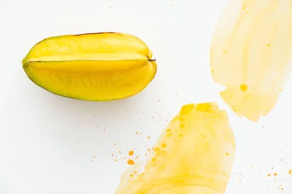 Elevated view of exotic sweet carambola on white surface with yellow watercolor — Stock Photo