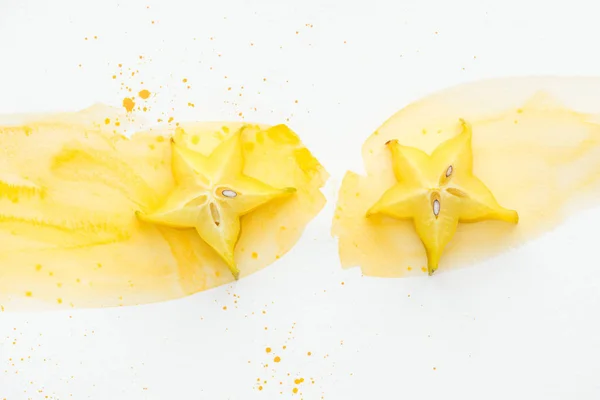 Vista superior de dos frutos estrella sobre superficie blanca con acuarela amarilla - foto de stock