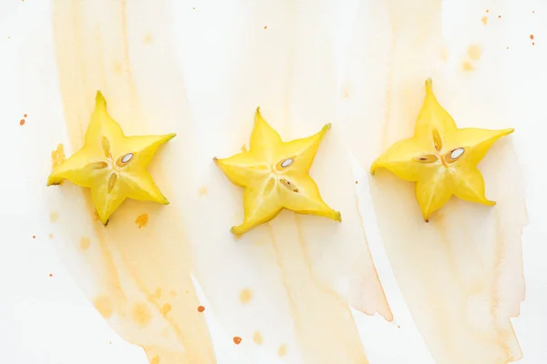 Top view of three star fruits on white surface with yellow watercolor — Stock Photo