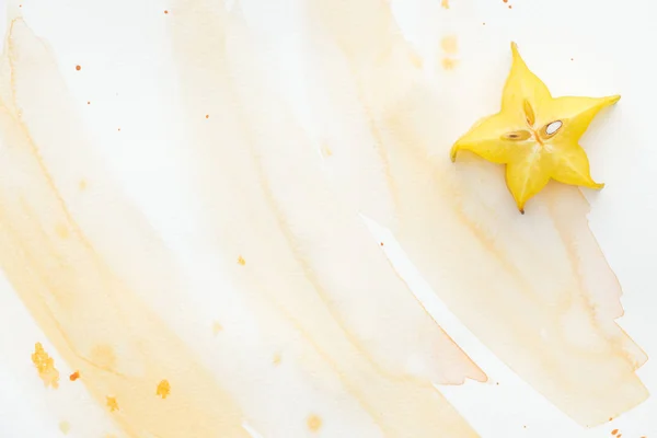 Top view of one ripe star fruit on white surface with yellow watercolor — Stock Photo