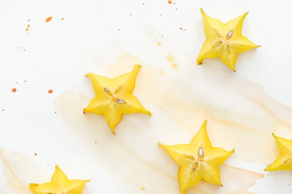 Top view of yellow star fruits on white surface with yellow watercolor — Stock Photo