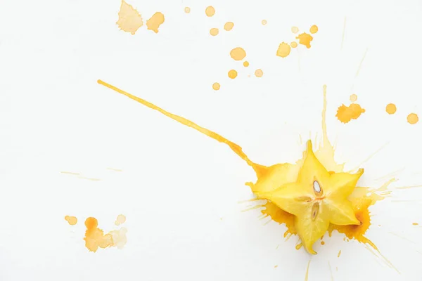 Vista superior de la fruta estrella exótica en la superficie blanca con salpicaduras de pintura amarilla - foto de stock